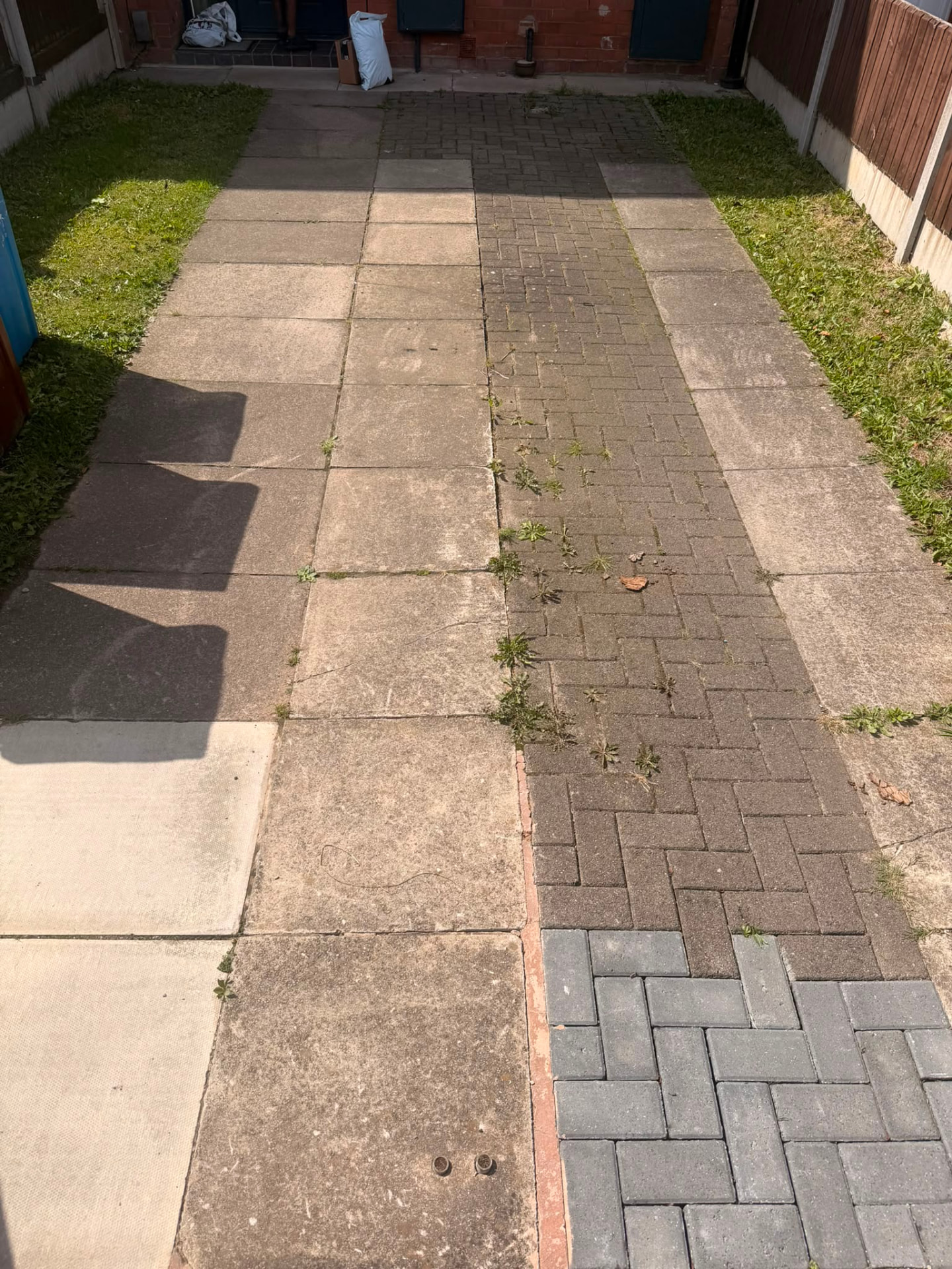 Manchester driveway with dirty, mossy paving slabs and weeds before pressure cleaning